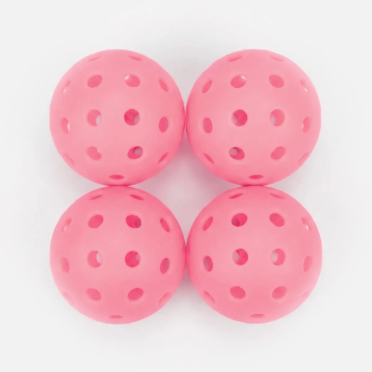 Four pink perforated balls on a white background